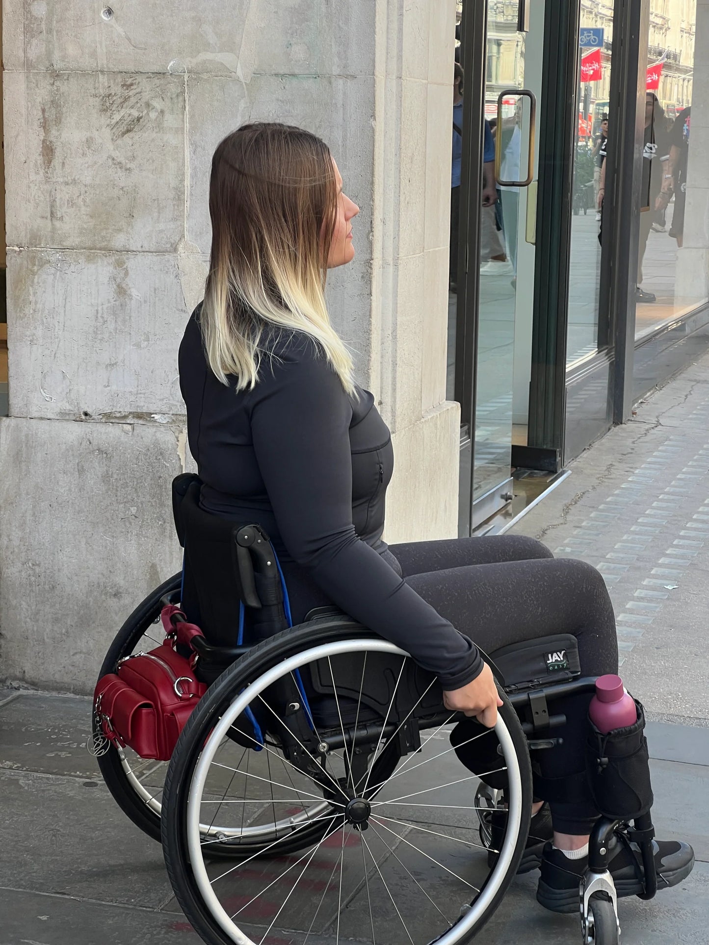 Wheelchair user wearing accessible shoulder bag attached to wheelchair while seated